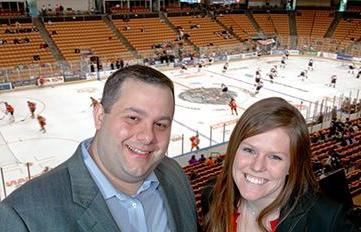 Image of a UNH student with an 校友 at a Wildcat hockey game