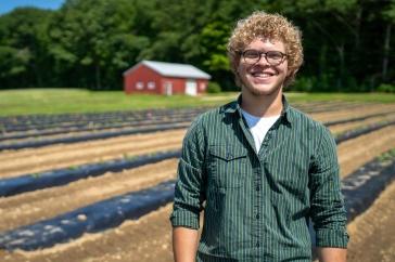 Eliudes营地Marcano, an exchange student from Puerto Rico, stands in a field at the Kingman Research Farm, 去年夏天，他在那里帮助支持联合国大学的农业研究.